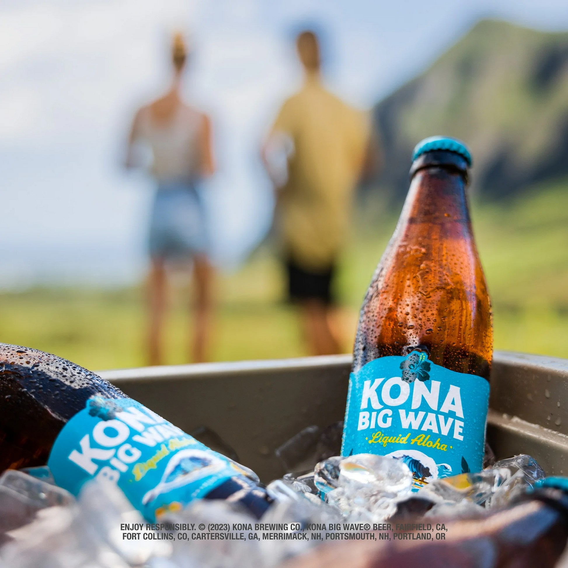 Kona Big Wave beer bottles in a cooler with people in the background