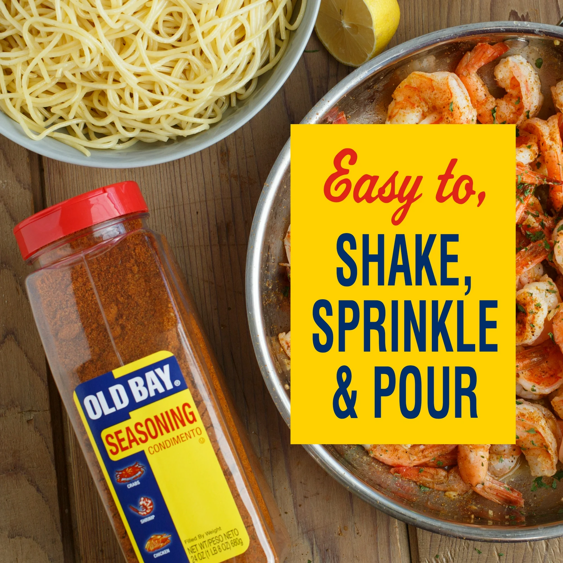Old Bay seasoning bottle with a bowl of pasta and shrimp on a wooden surface.